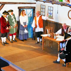 Der Waffenmeister aus Dresden beim Vollmarshäuser Bürgermeister, die Darsteller*in (v.l.n.r.) Harald Wolf (H.Caspar Naehler), Klaus Michel (Johannes Schütz), Pia Bischoff (Nelly), Wilfried Kehl (1. Schöffe), Günther Söllner (Bürgermeister), Ingo Hartung (2. Schöffe) und Michael Friedrich (Waffenmeister aus Dresden).