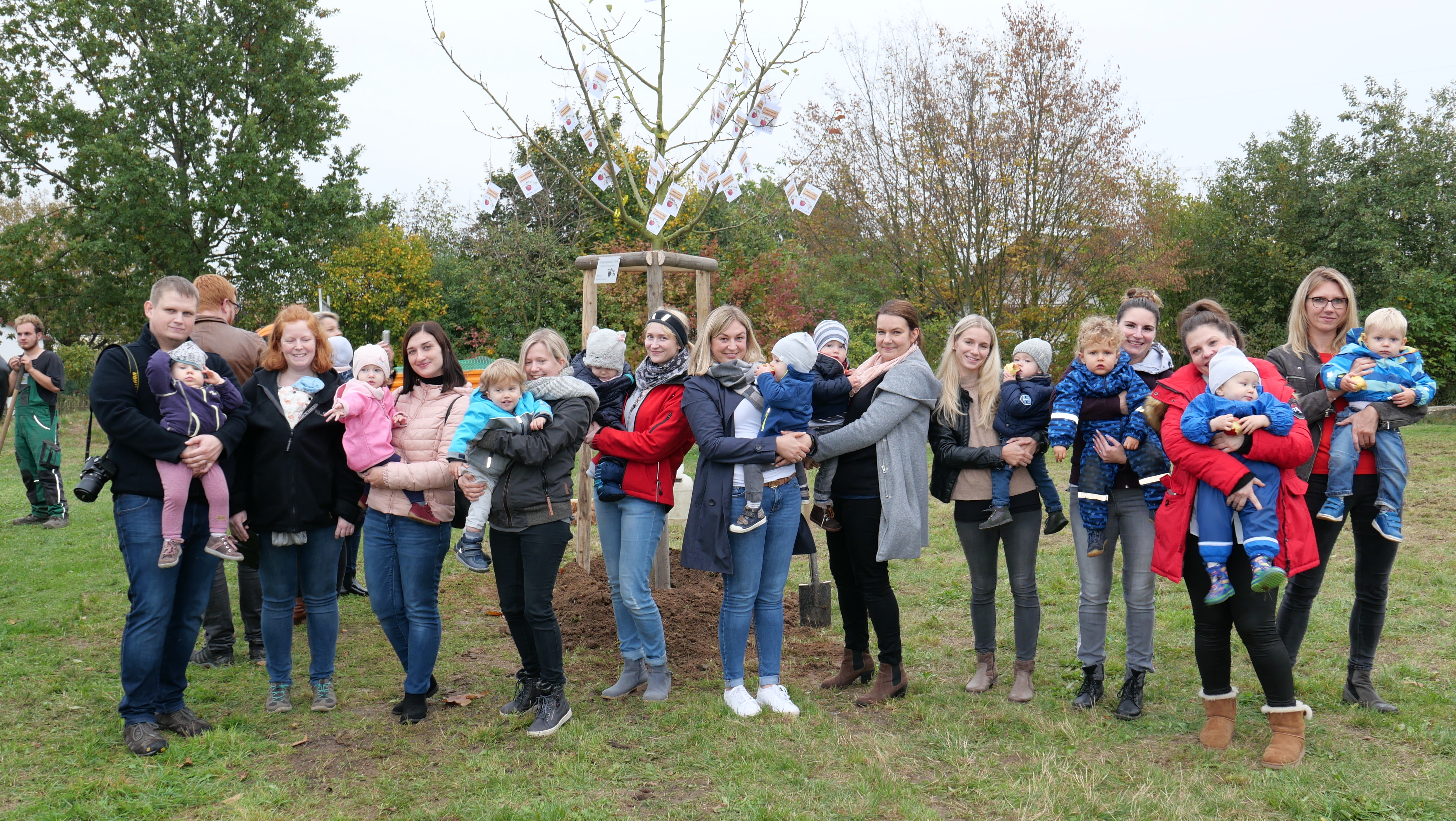 Ein Teil der über 30 Kinder, die am 23.10. bei der Pflanzung ihres Geburts-Apfelbaumes dabei waren mitsamt ihren Eltern und den Äpfeln mit den guten Wünschen, die der Bürgermeister Uwe Jäger an alle Gäste verteilte.  
