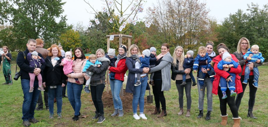 Ein Teil der über 30 Kinder, die am 23.10. bei der Pflanzung ihres Geburts-Apfelbaumes dabei waren mitsamt ihren Eltern und den Äpfeln mit den guten Wünschen, die der Bürgermeister Uwe Jäger an alle Gäste verteilte.  