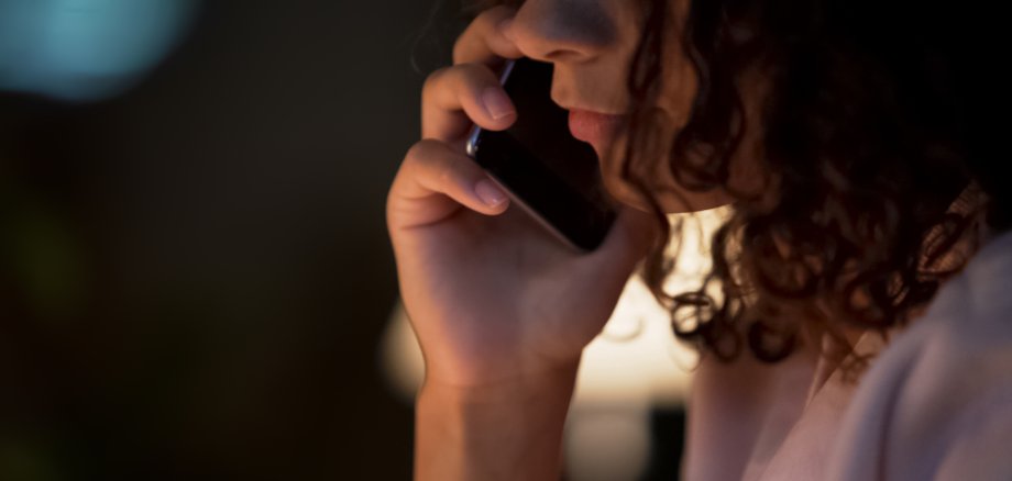 Depressed mixed-race female talking on smartphone with sadness, face closeup