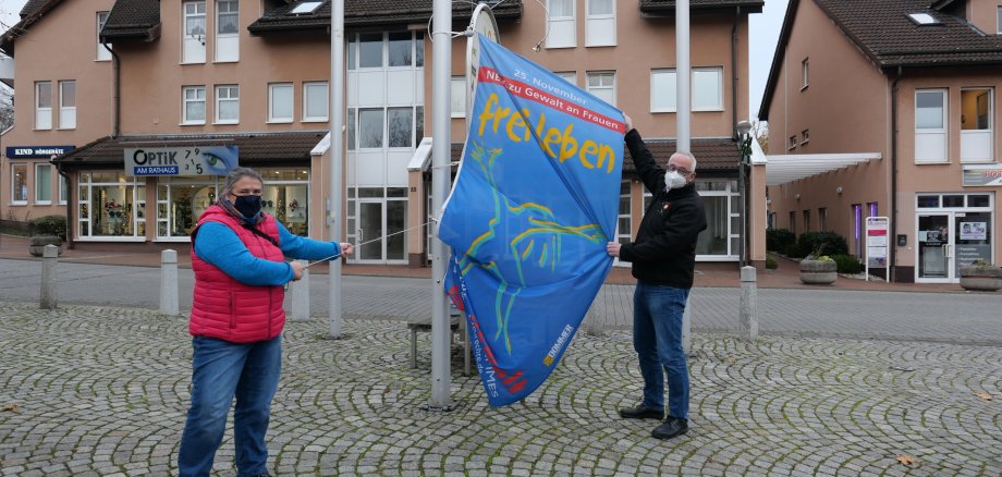 Frauenbeauftragte Lena Steffek-Herbold (l.) und Bürgermeister Uwe Jäger hissten am 25.11. die Fahne „Frei leben – ohne Gewalt“ als Zeichen zur Beseitigung von Gewalt gegen Frauen, Corona-bedingt in diesem Jahr unter Ausschluss der Öffentlichkeit, auf dem Rathausvorplatz.