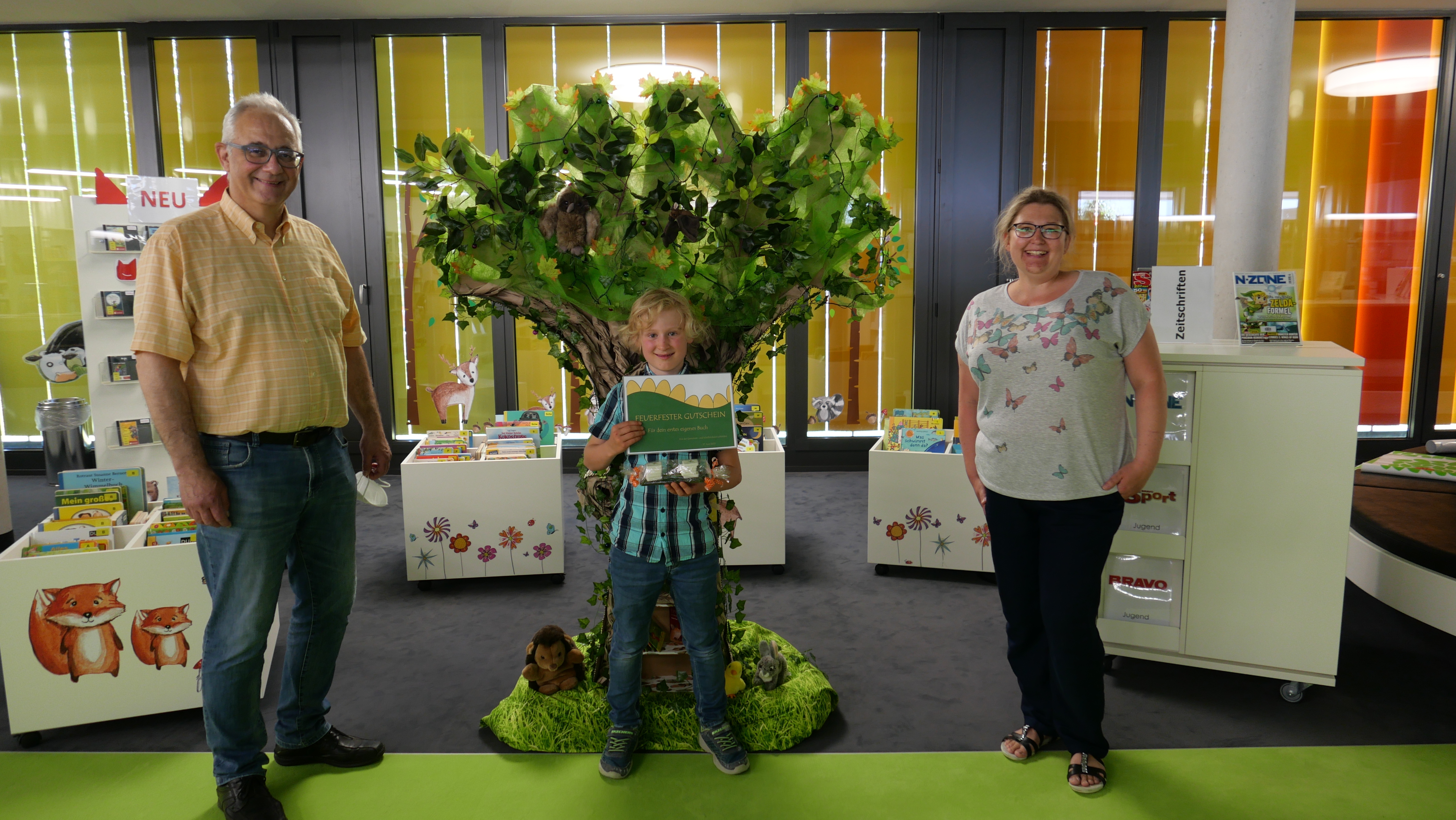 Leiterin der Gemeinde- und Schulbücherei Sabrina Bieberstedt (r.) gratulierte am 17.06. gemeinsam mit Bürgermeister Uwe Jäger (l.) dem jungen Lohfeldener Kinderbuchautor Mathis Strüwing (M.) zu seinen Büchern und überreichte ihm einen Gutschein für den Druck eines großen Sammelbandes seiner Drachengeschichten sowie ein Fauchie-Marketingpaket.