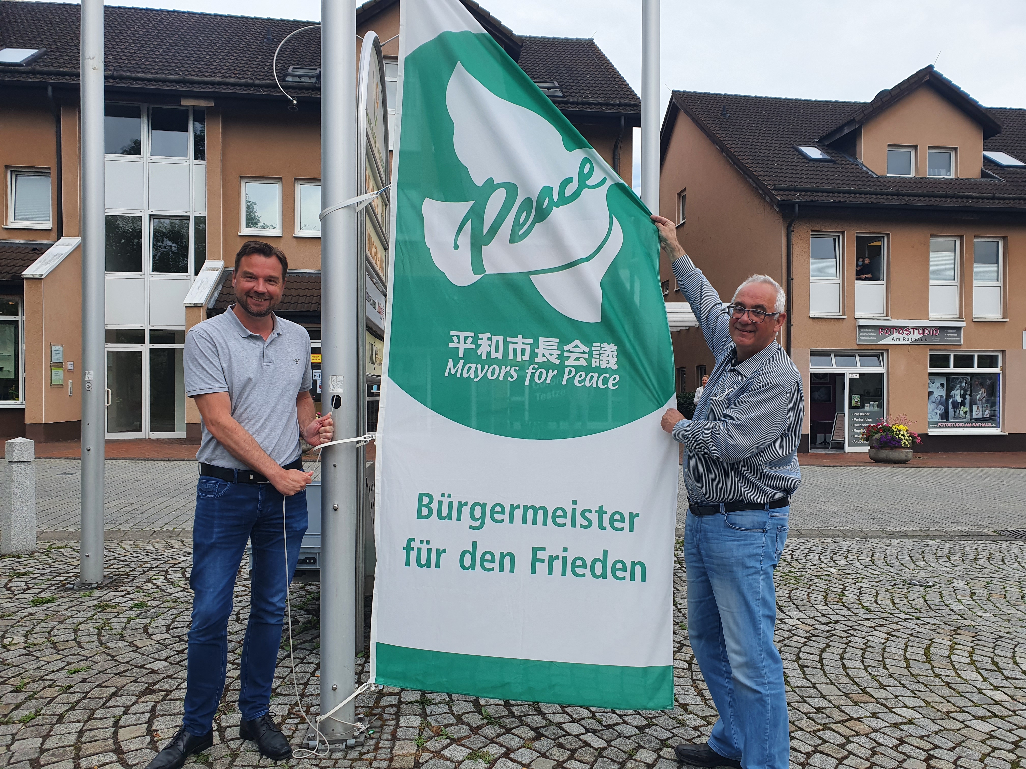 Bürgermeister der Gemeinde Lohfelden, Uwe Jäger (r.), hisste zusammen mit Leiter des Fachbereichs Verwaltung und Ordnung, Kai Hast, die Mayors for Peace-Flagge. 