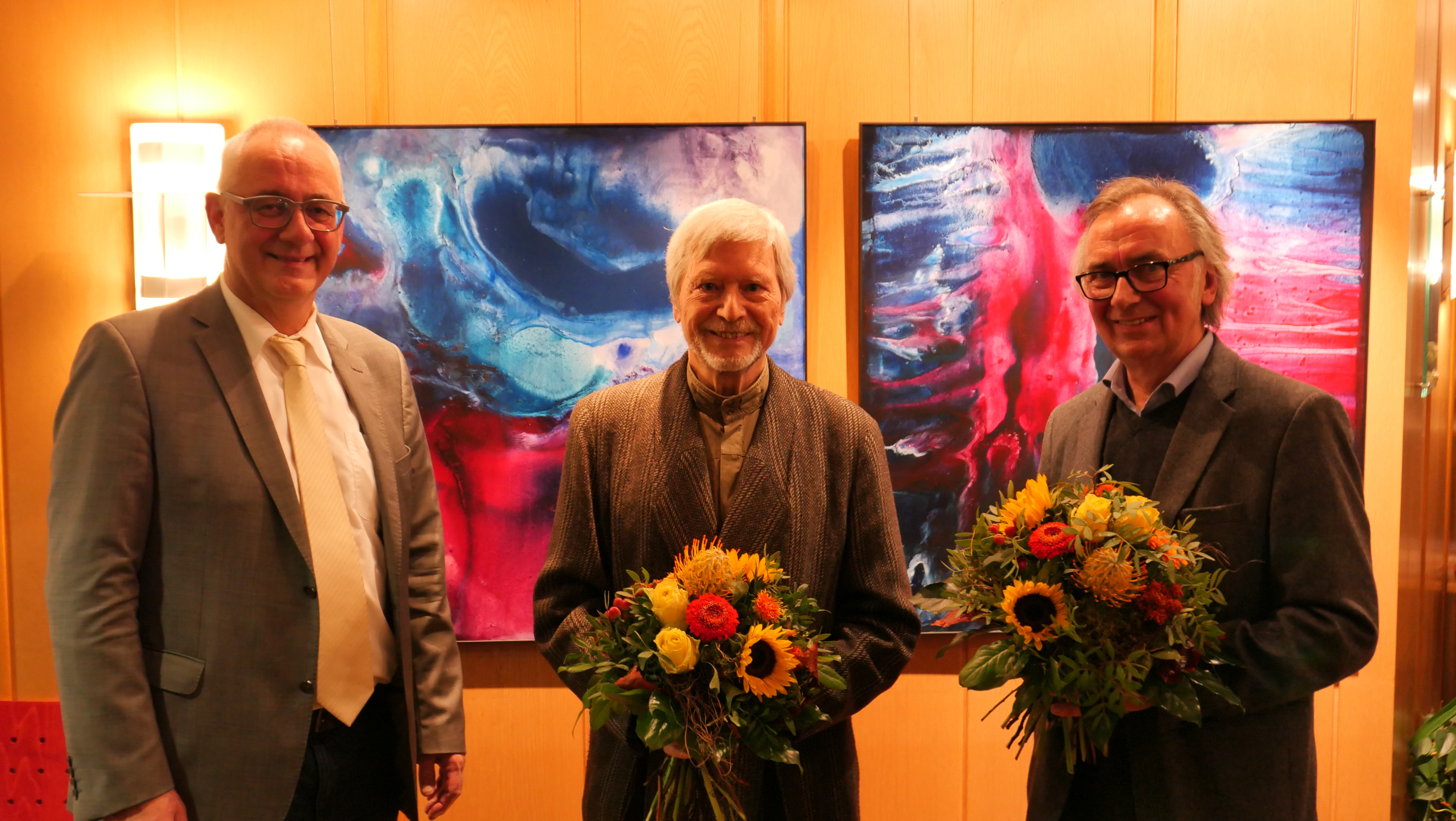 Bürgermeister Uwe Jäger (l.) bedankte sich mit einem Blumenpräsent für die gelungene Ausstellungseröffnung bei den Künstlern Prof. Dr. Gernot Minke (M.) und Wolfgang Loewe.