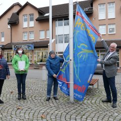 Frauenbeauftragte Lena Steffek-Herbold (3.v.l.) und Bürgermeister der Gemeinde Lohfelden Uwe Jäger hissten am 25.11. gemeinsam mit einigen interessierten Bürgerinnen die Fahne „Frei leben – ohne Gewalt“ als Zeichen zur Beseitigung von Gewalt gegen Frauen auf dem Dr.-Walter-Lübcke-Platz vor dem Rathaus. - Link öffnet seitenüberlagerndes Dialog-Fenster