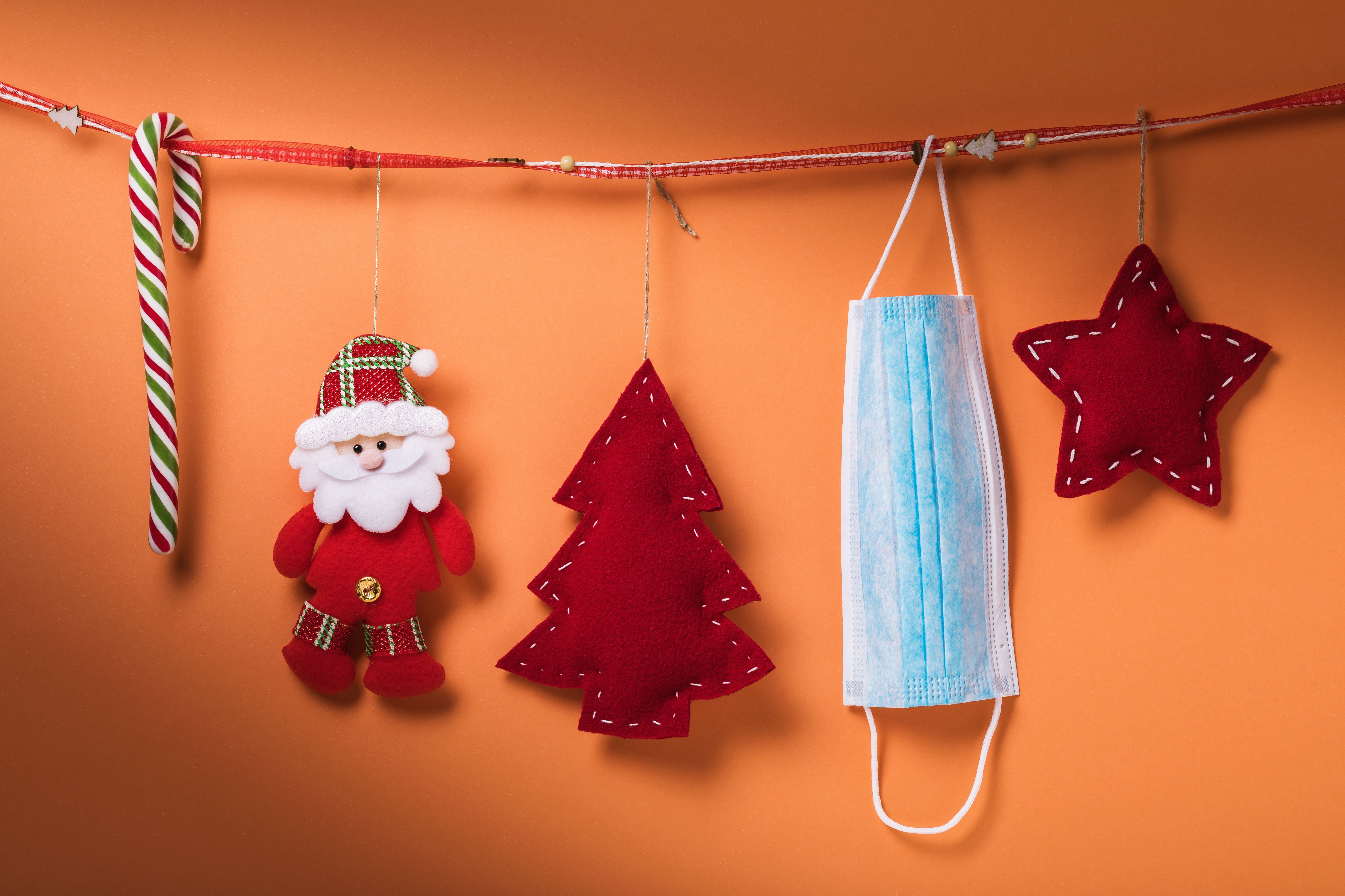 Auf dem Foto ist eine Weihnachtsdekoration, zu der auch eine hellblaue medizinische Atemschutzmaske gehört, zu sehen. 