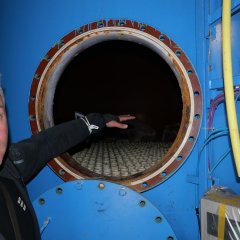 Der zuständige Fachbereichsleiter Thorsten Bürgel zeigt, wo Kies und Kohle eingefüllt werden, um das Wasser im Schwimmbecken sauber zu halten.