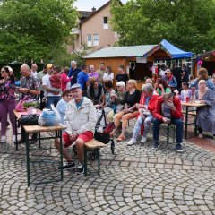 Gäste auf den Bierzeltgarnituren vor den Hütten.