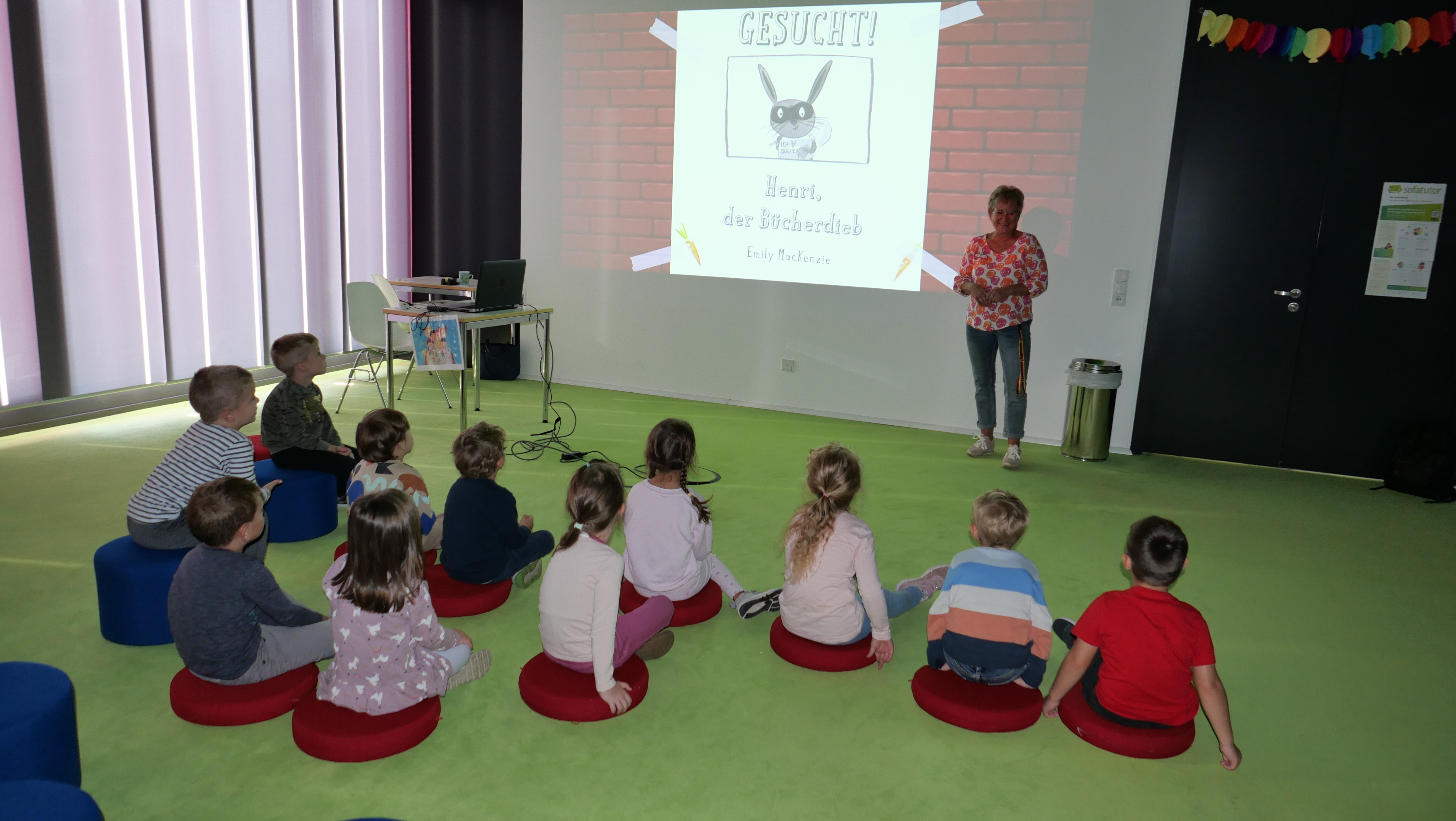 Die kleinen Besucherinnen und Besucher lauschen der Geschichte von Henri, dem Bücherdieb.