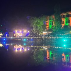 Rathaus Lohfelden im Dunklen, angestrahlt in orange und grün; Wasser im Vordergrund; beleuchtete Bühne links.