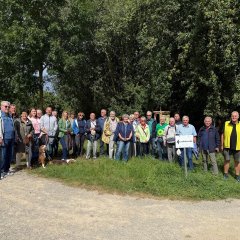 Gruppenbild mit ca. 30 Personen vor grünen Bäumen.