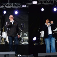 Frau und Mann auf einer Bühne mit Musikinstrumenten der Madison Event Band im Hintergrund.