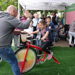 Kind auf einem Fahrrad wird von Mann angefeuert.