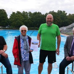 Bürgermeister Uwe Jäger steht gemeinsam mit der Jubilarin und den beiden Schwimmmeistern vor dem Schwimmbecken im Freibad Lohfelden.