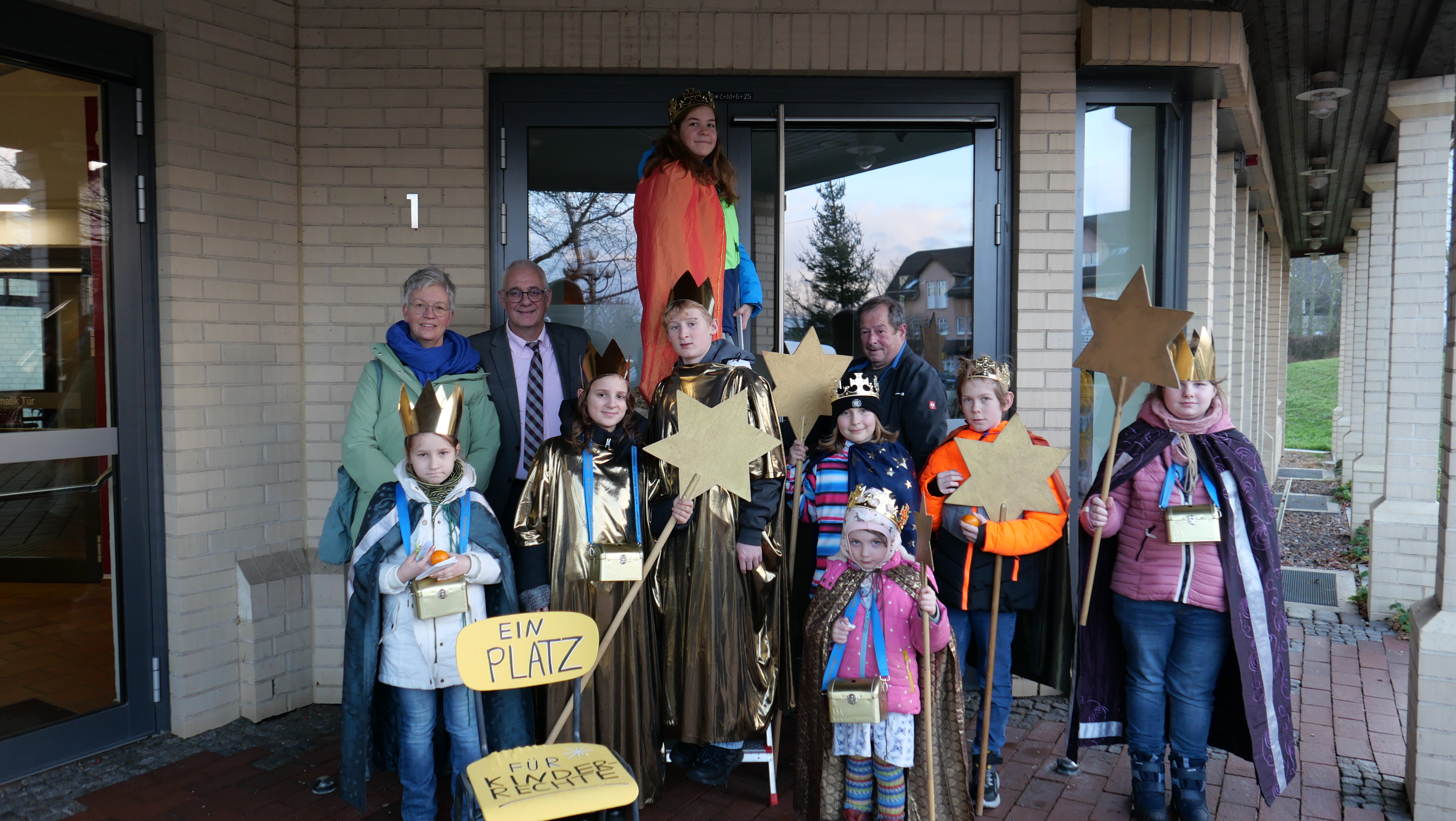 Gut gesichert von Bürgermeister Uwe Jäger (2.v.l.) und Sandra Gemke (l.) brachte die Sternsingerin Sarah von Bistram (M.) den Segen für 2025 über der Eingangstür des Rathauses an.