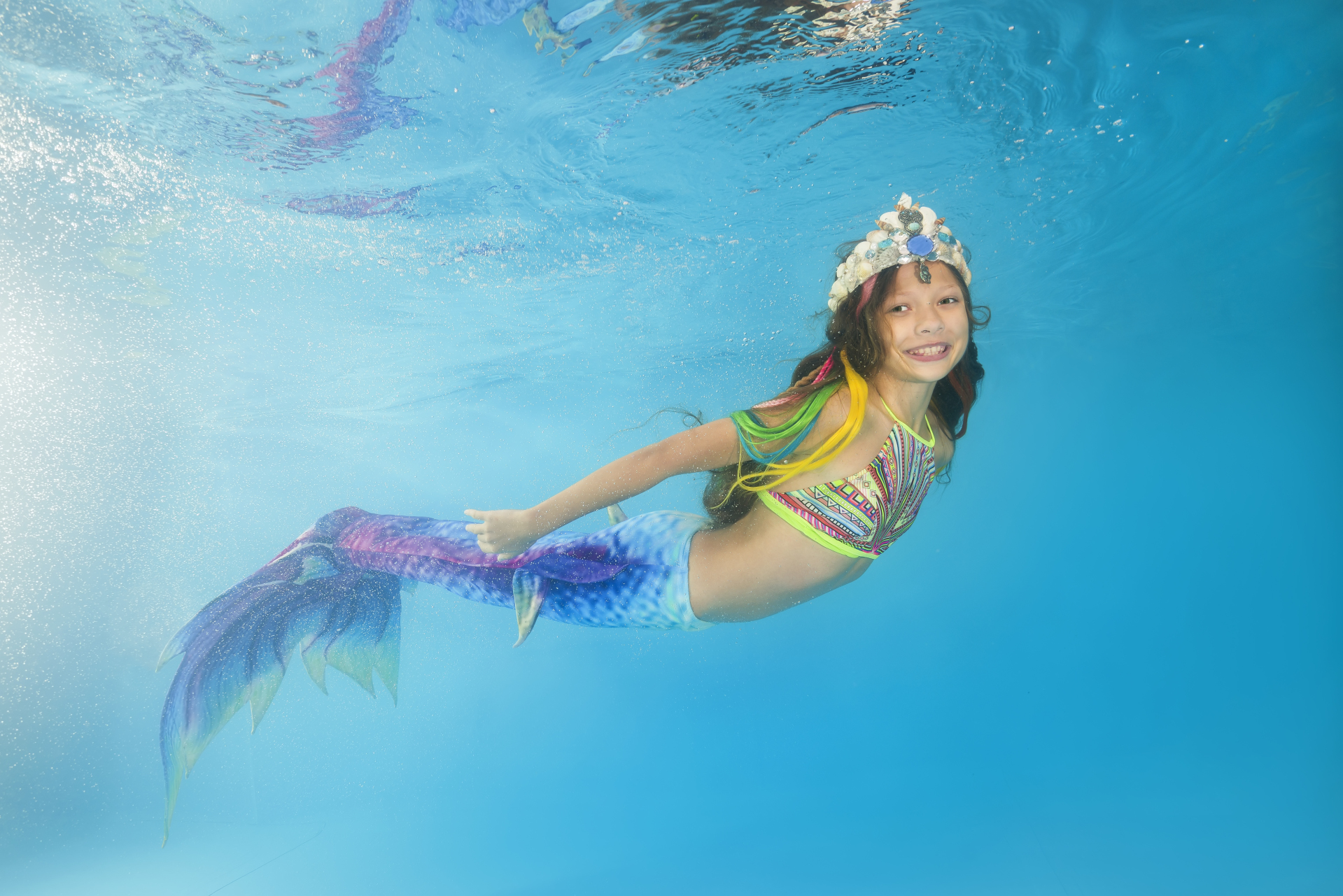 A girl in a mermaid costume poses underwater in a pool. Young beautiful girl poses underwater in the pool. A girl in a mermaid costume poses underwater in a pool. Young beautiful girl poses underwater in the pool.