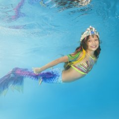 A girl in a mermaid costume poses underwater in a pool. Young beautiful girl poses underwater in the pool.