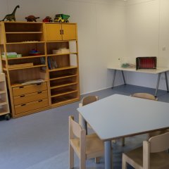 Container-Anlage - Innenraum, blauer Fußboden, Regale, kleine Gruppentisch mit Stühlchen für Kinder