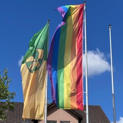 Die Regenbogenfahne steht für Toleranz, Offenheit und Stolz. Die Farben auf der Flagge stehen für Diversität und richten sich gegen jede Art von Diskriminierung. Die Regenbogenflagge wird gehisst, um Solidarität und Verbundenheit zur LGBTQIA+-Szene zu zeigen.