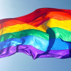 Rainbow flag, sun, wind, and blue sky