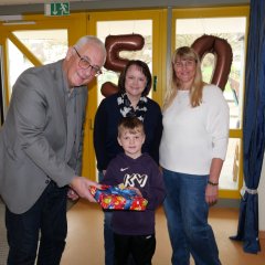 Bürgermeister Uwe Jäger übergibt gemeinsam mit Tanja Hammer, Leiterin des Sachgebiets Kindertagesstätten (M.), und komm. Leiterin der KiTa Ochshausen, Sandra Schiffmann, eines der Geschenke stellvertretend für alle Kinder der KiTa Ochshausen an Vorschulkind Lukas
