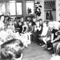 Die damalige KiTa-Leiterin Emma Röttger (l.) gemeinsam mit einer Gruppe von Kindern im Eingangsbereich der Kindertagesstätte.