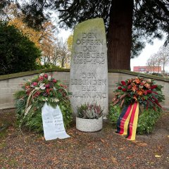 Ehrenmal mit 2 Kränzen davor mit beschrifteten Trauerschleifen von der Gemeinde Lohfelden und dem VdK.