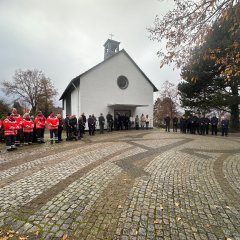 Alle Teilnehmenden vor der Friedhofskapelle, Platz mit Kopfsteinpflaster im Vordergrund.