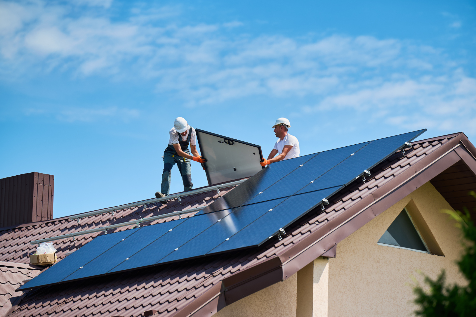 Workers building solar panel system on roof of house. Installers carrying photovoltaic solar module