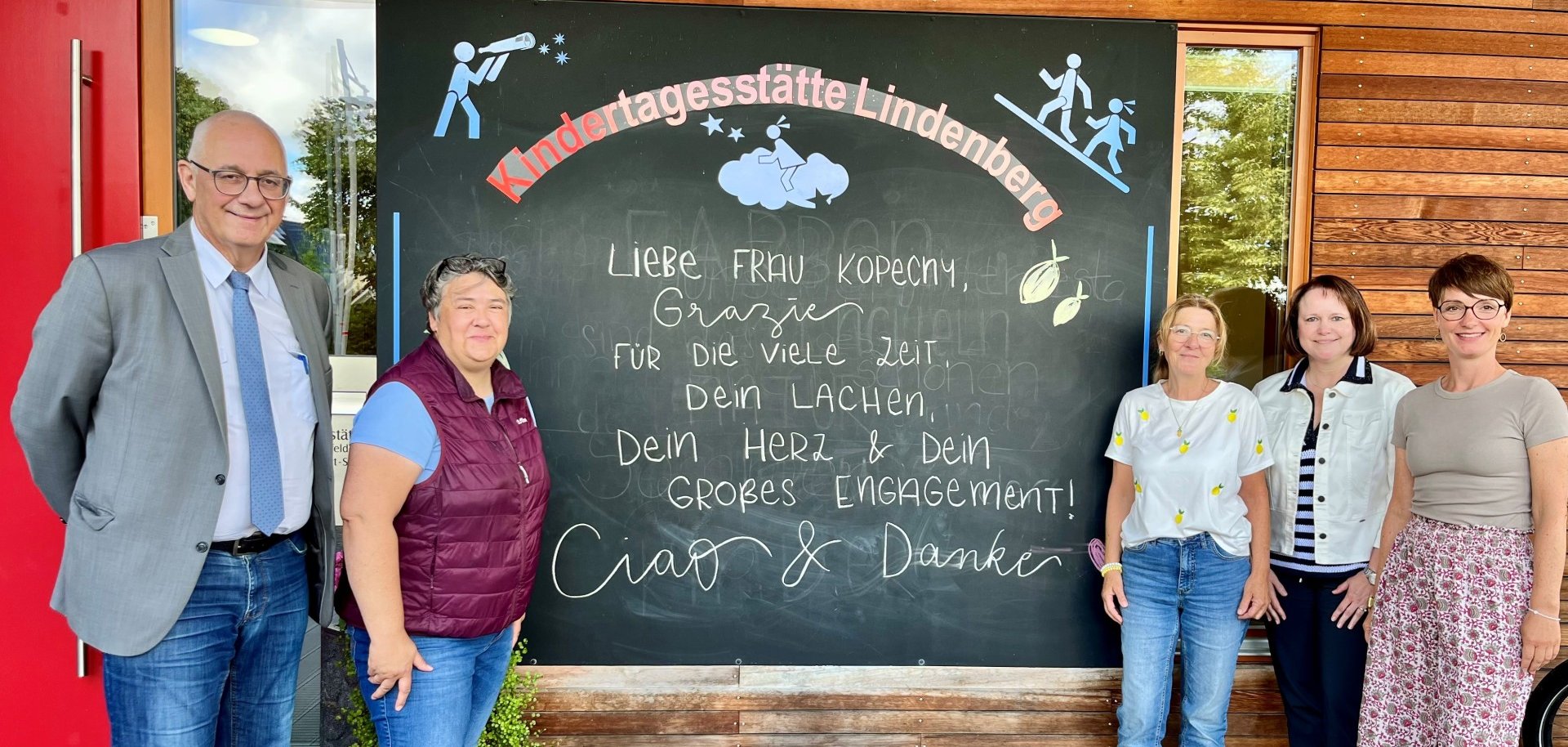 Verantwortliche der Gemeinde Lohfelden stehen vor Kita Lindenberg und verabschieden Kollegin  Simone Kopecny in den Ruhestand