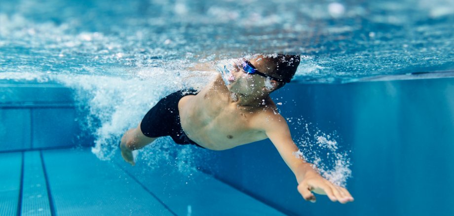 Junge schwimmt im Freibad und krault Junge schwimmt im Freibad und krault