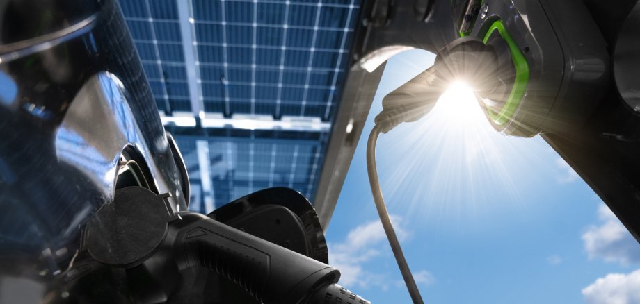 Electric car is charged from a charging station that takes energy from solar panels. Solar carport. Close up Electric car is charged from a charging station that takes energy from solar panels. Solar carport. Close up