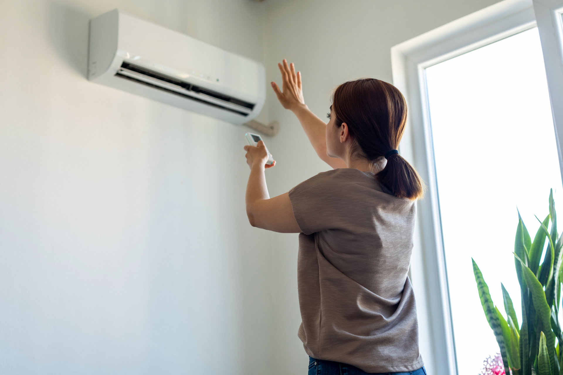 Frau schaltet Klimaanlage in Wohnung ein