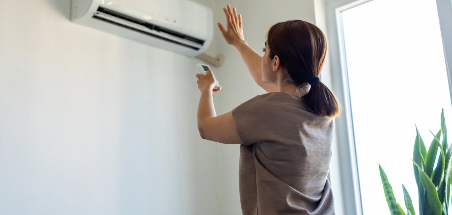 Frau schaltet Klimaanlage in Wohnung ein