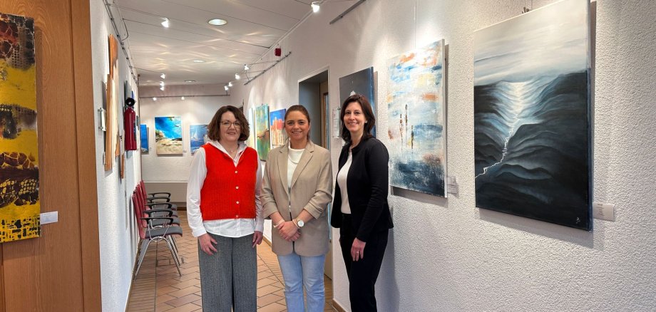 Senioren-Beauftragte Katharina Schaub steht im Rathausflur zusammen mit zwei Kolleginnen.