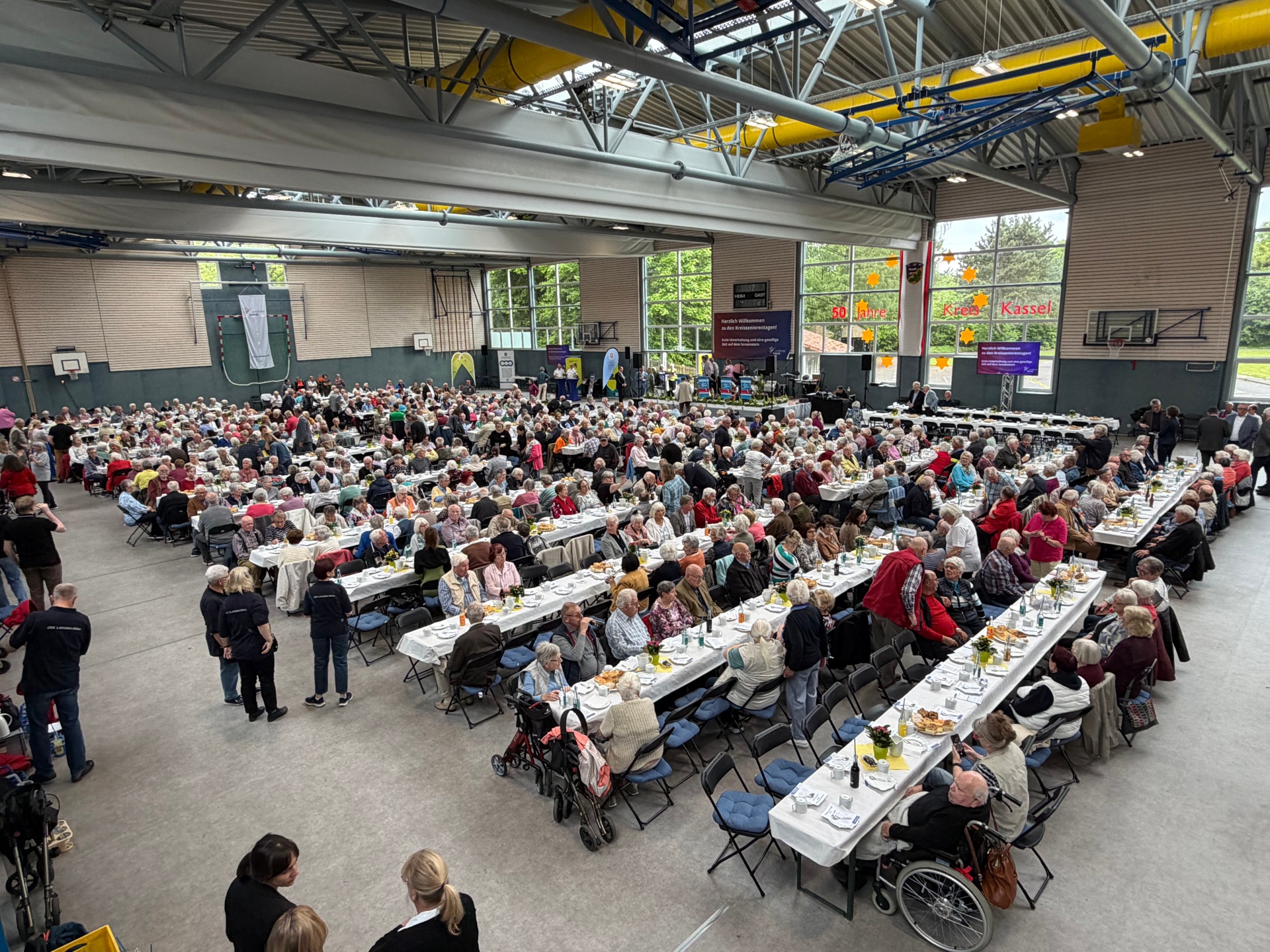 Blick von oben auf die Tischreihen mit Seniorinnen und Senioren.