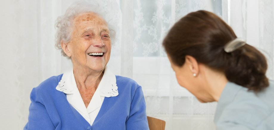Seniorin lacht ihr Gegenüber an, beide spielen ein Brettspiel. Seniorin lacht ihr Gegenüber an, beide spielen ein Brettspiel.