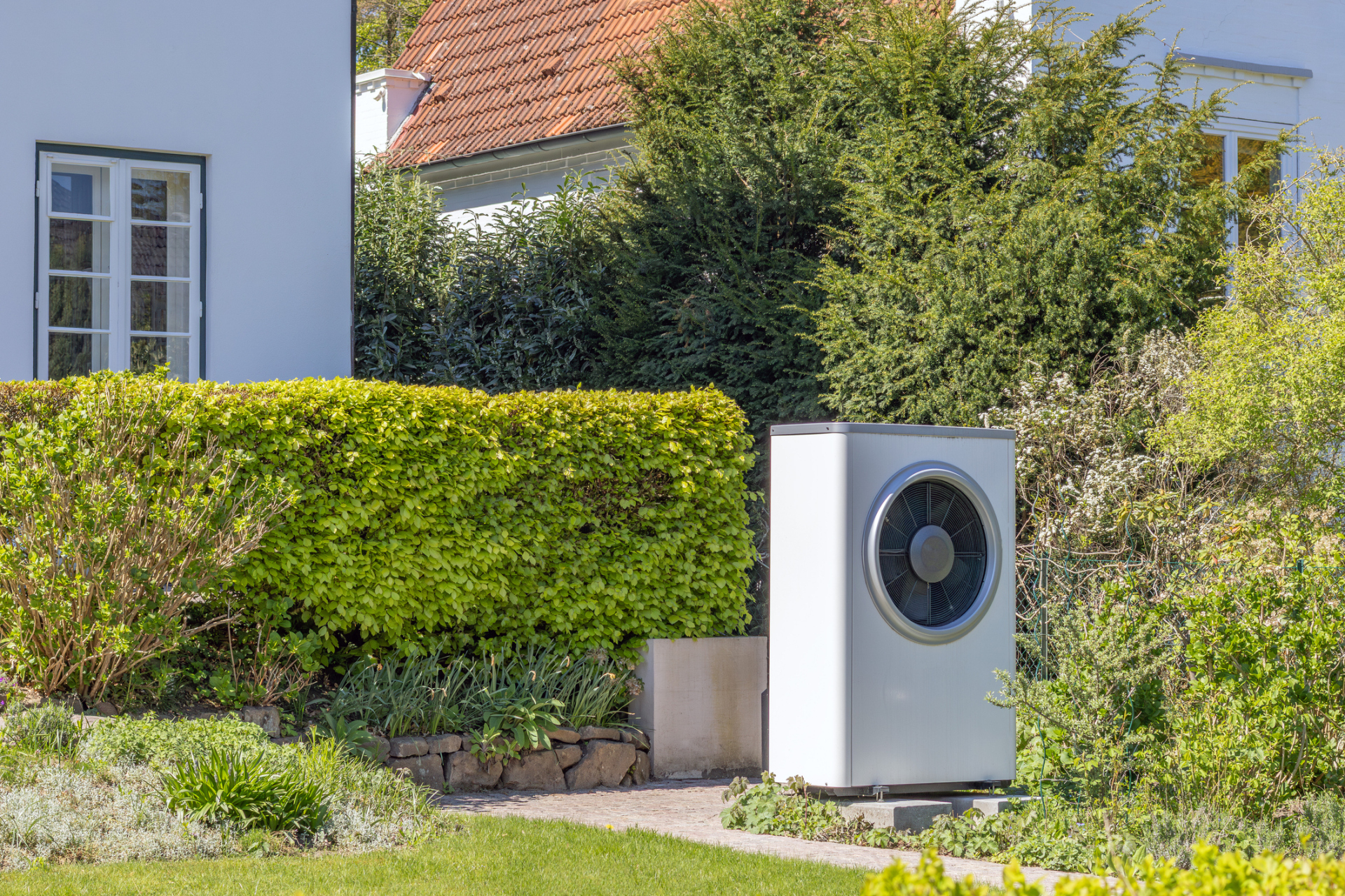 Ansicht einer Wärmepumpe im Garten vor einem Einfamilienhaus