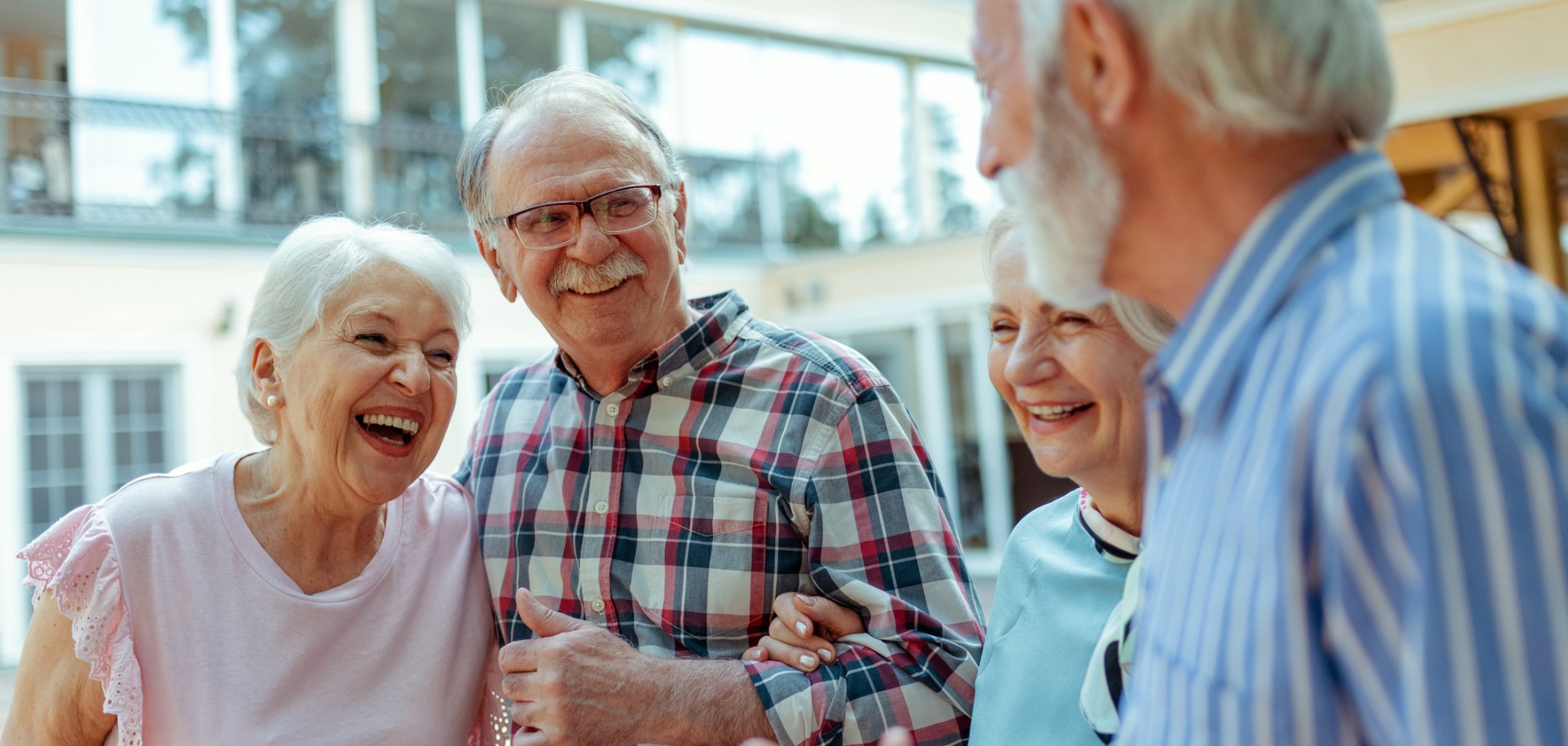 Vier Senioren stehen zusammen und lachen gemeinsam Vier Senioren stehen zusammen und lachen gemeinsam