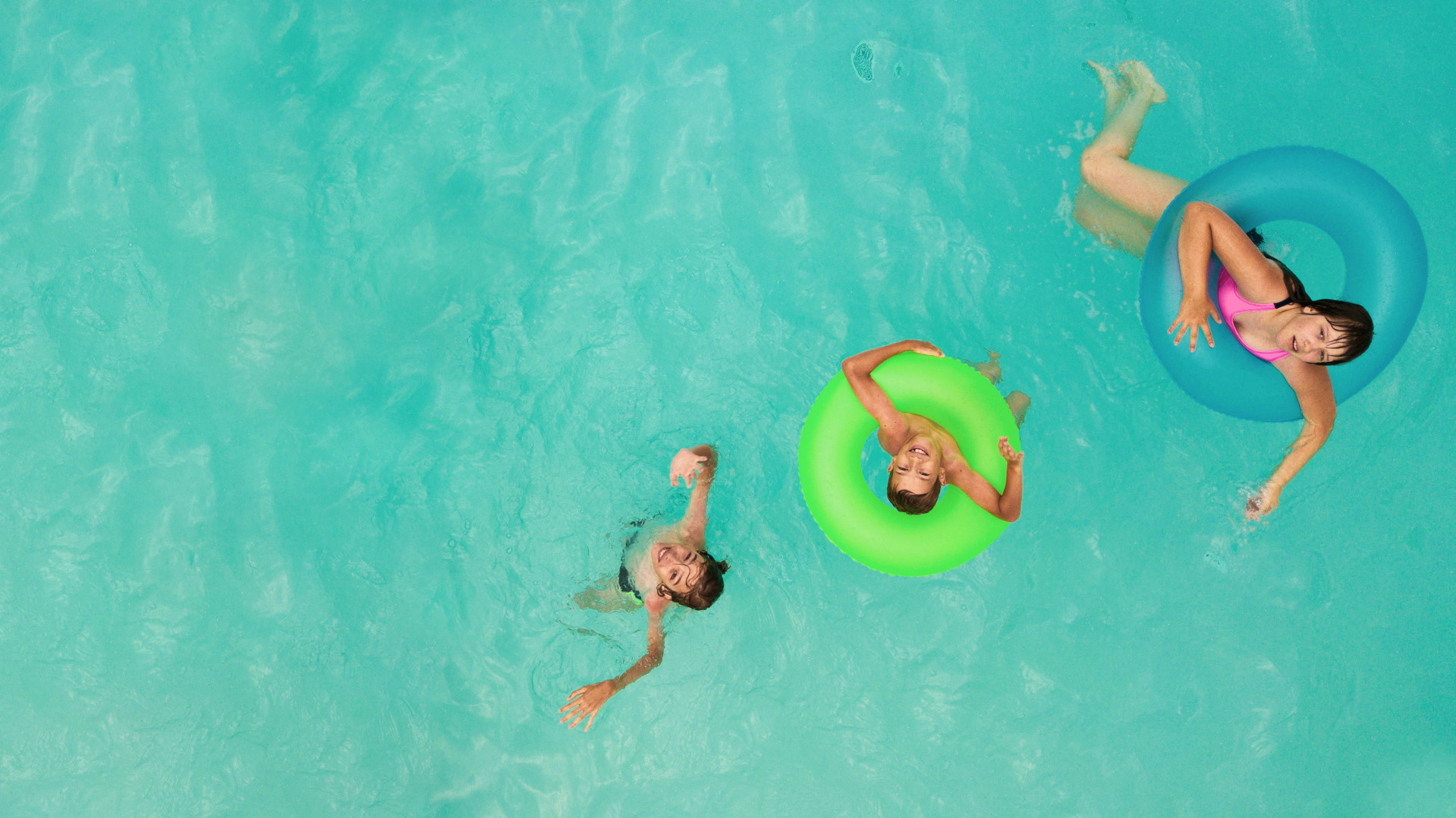 Kinder schwimmen im Wasser mit Schwimmringen