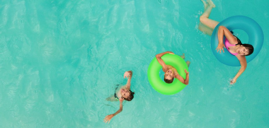 Kinder schwimmen im Wasser mit Schwimmringen Kinder schwimmen im Wasser mit Schwimmringen