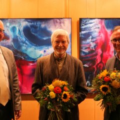 Bürgermeister Uwe Jäger (l.) bedankte sich mit einem Blumenpräsent für die gelungene Ausstellungseröffnung bei den Künstlern Prof. Dr. Gernot Minke (M.) und Wolfgang Loewe.