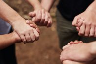 Ausgeschnittene Aufnahme einer Gruppe unerkennbarer Menschen, die sich in der Natur an den Händen halten.