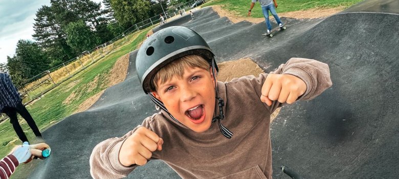 Begeisterung bei allen Nutzenden! Junge mit Helm macht die Daumen hoch, im Hintergrund die Pumptrackanlage Lohfelden.