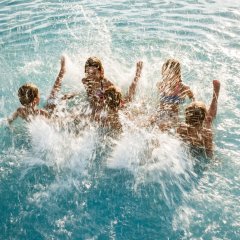 Gruppe von Jugendlichen plantscht im Freibad.