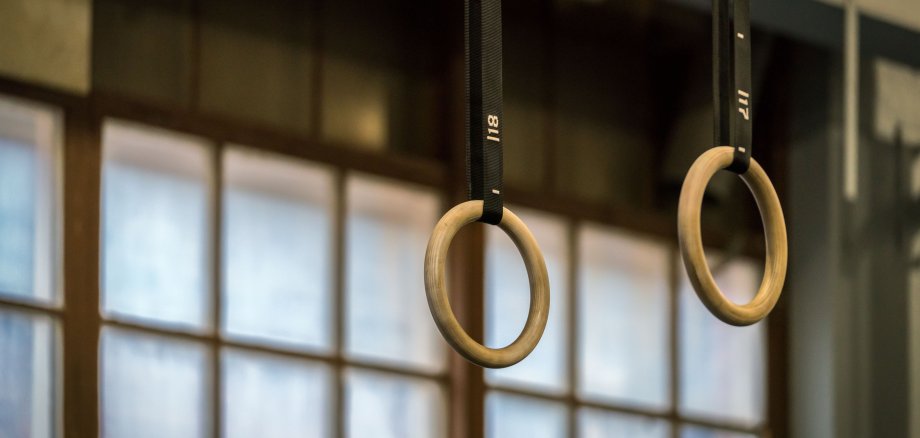 Selektiver Fokus auf hölzerne Gymnastikringe vor einem großen Fenster.