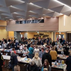 Saal Ochshausen im Bürgerhaus Lohfelden; Tischreihen mit vielen Büchern; gut besucht; Bühne im Hintergrund