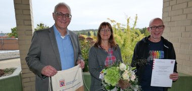 Bürgermeister Uwe Jäger (l.) gratuliert den Vertretenden des Projektes „Angekommen in Deutschland", Maike Oertel und Jörg Ruckel, zum 2. Platz beim Hessischen Integrationspreis, der am 10. Oktober 2023 in Wiesbaden verliehen wurde.  