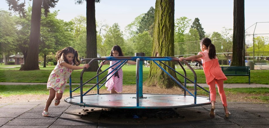 3 Kinder spielen auf einem Spielplatz.