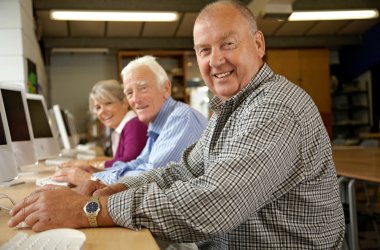 Mature woman and two mature men in computing class, portrait